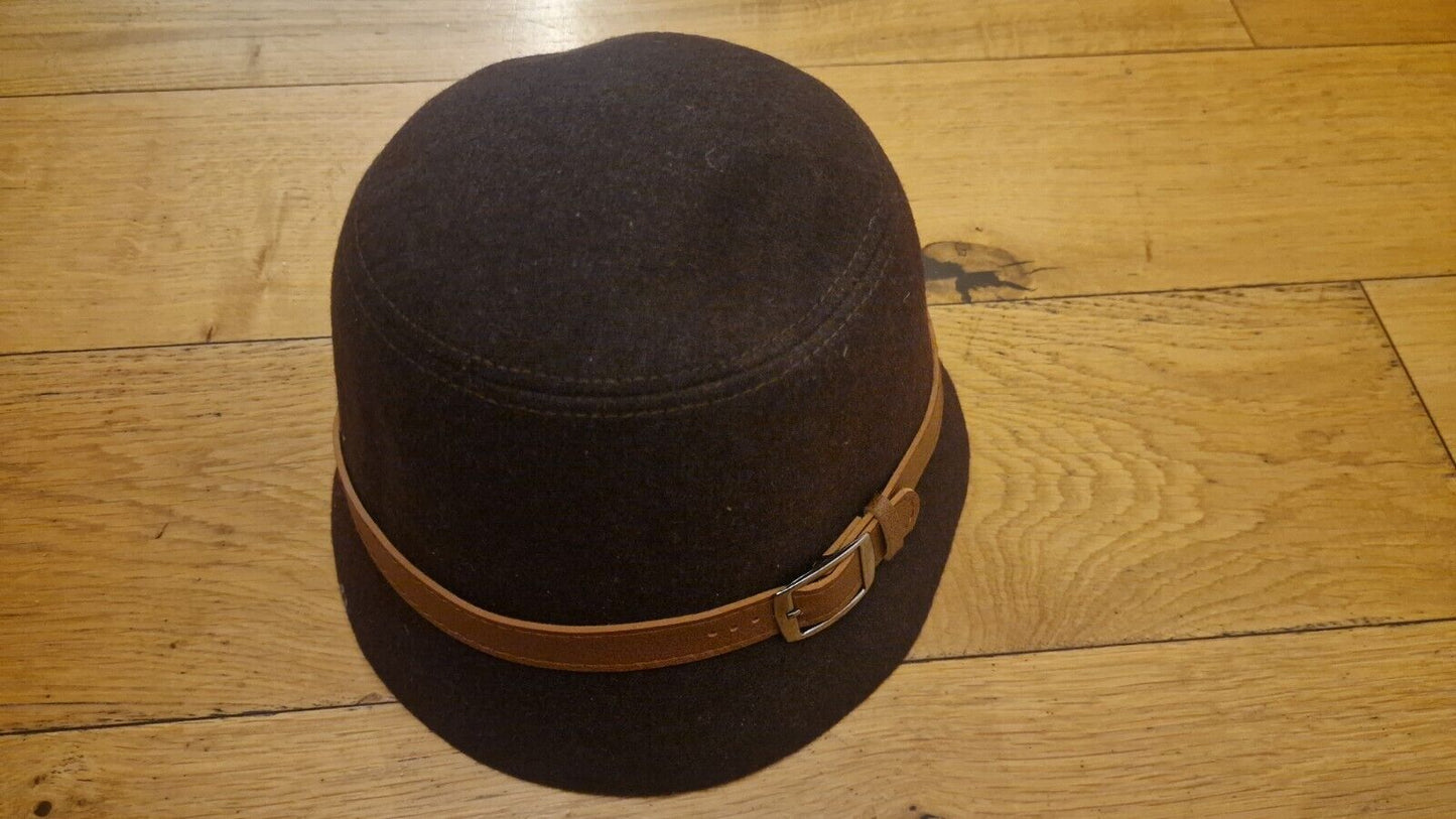 1940s style women's hat in dark brown with a tan buckle band on wooden floor background