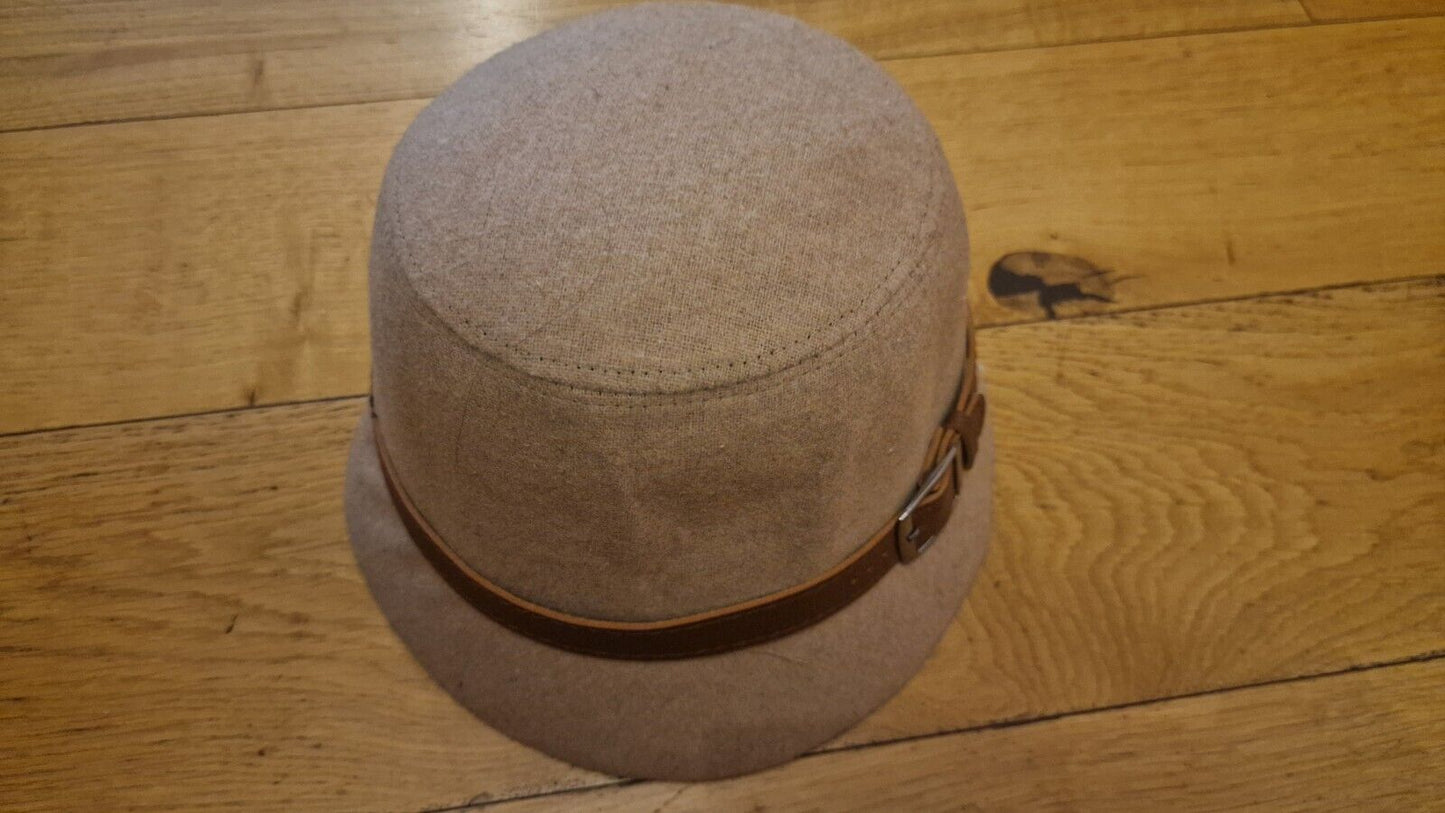 1940s style women's hat in beige with brown leather strap detail on wooden surface