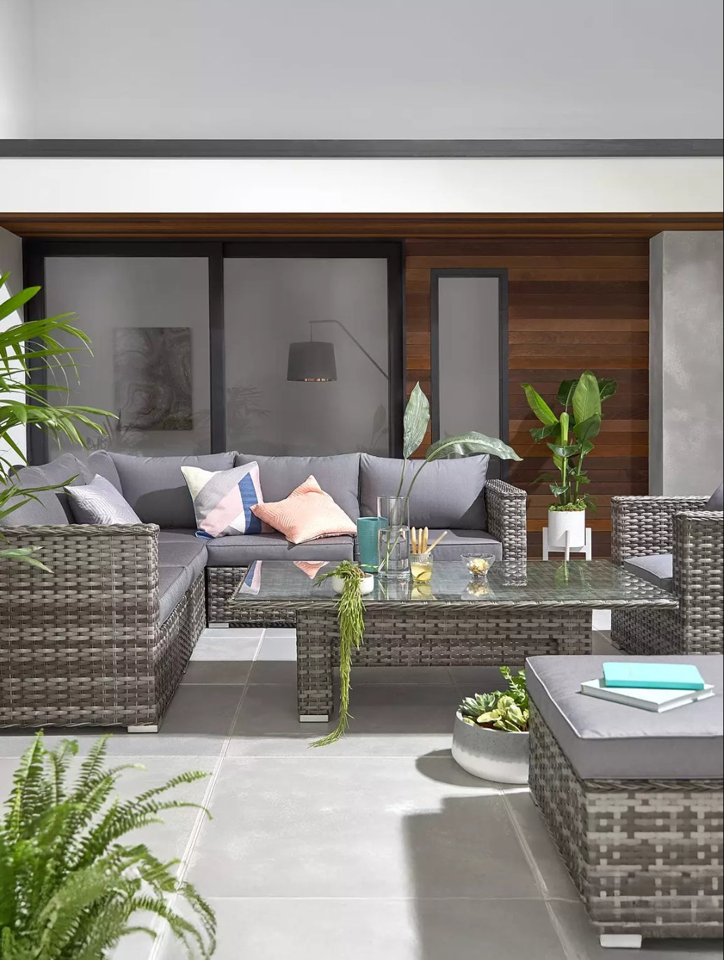Aruba 6 seater corner cushion set in grey rattan with a glass coffee table and vibrant decor