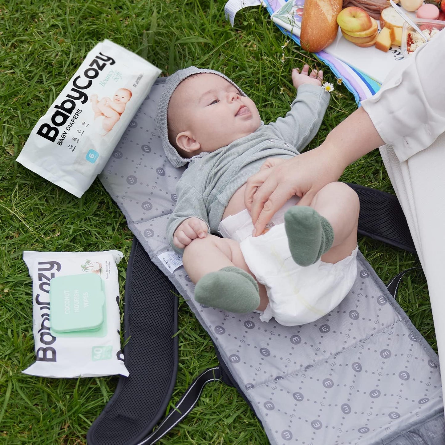 Babycozy size 3 diapers on changing mat with a happy baby in casual outfit on grass