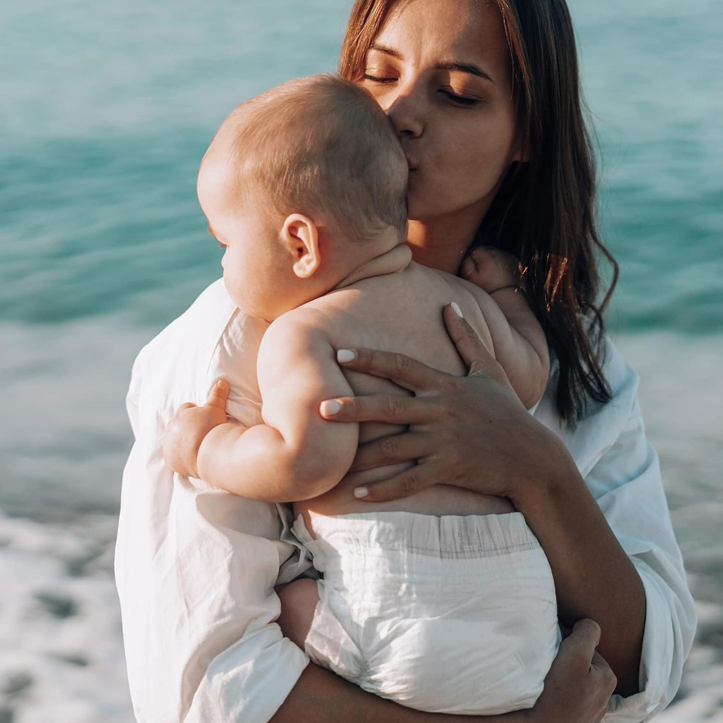 Mother holding baby wearing Babycozy size 3 diapers by the seaside on a sunny day