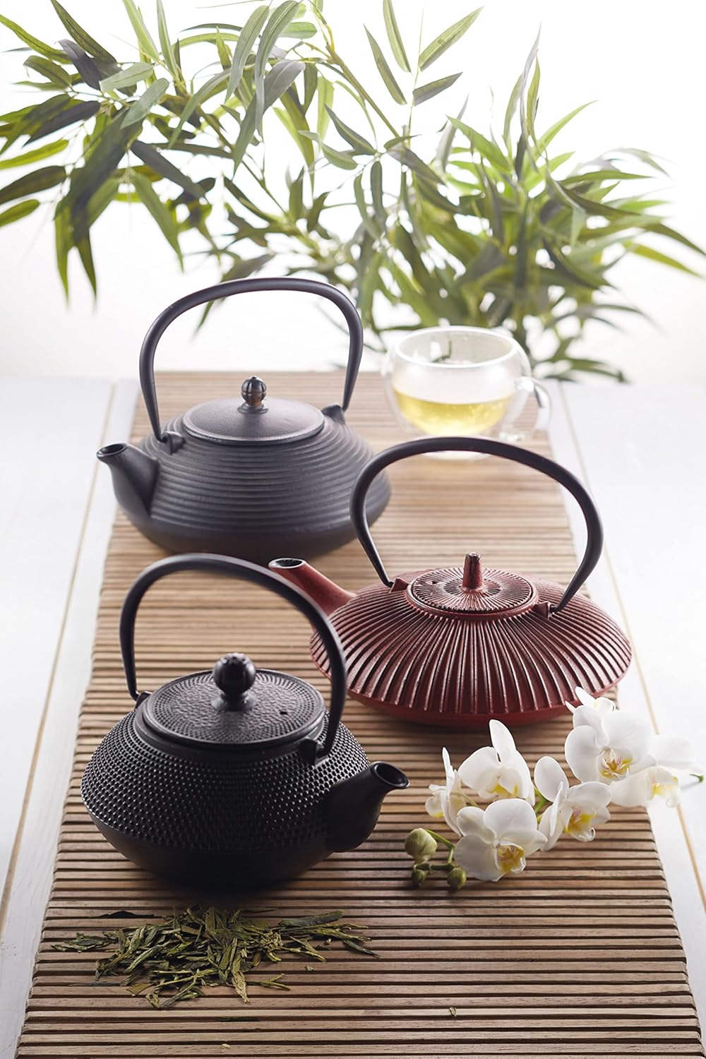 La Cafetière cast iron Japanese teapot set with elegant designs on a wooden table surrounded by greenery