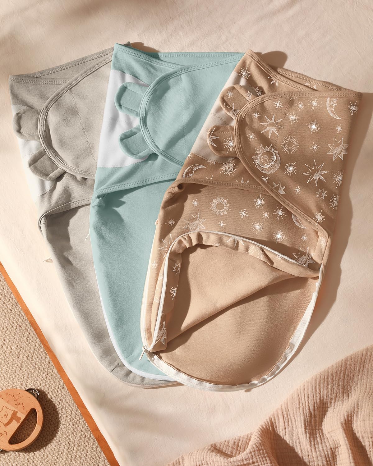 Set of three cotton baby swaddles with zipper in pastel colours, featuring cute celestial designs.