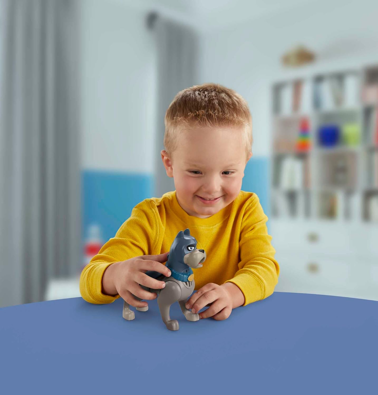 Child playing with Fisher-price DC Super Pet League Ace talking toy on a blue table