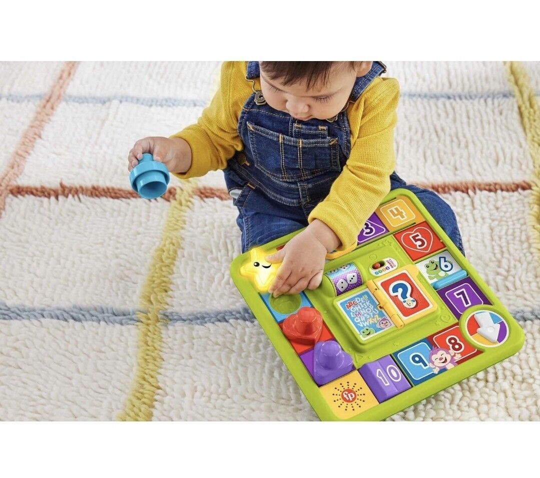Child engaging with Fisher-Price interactive activity board featuring colourful shapes and numbers