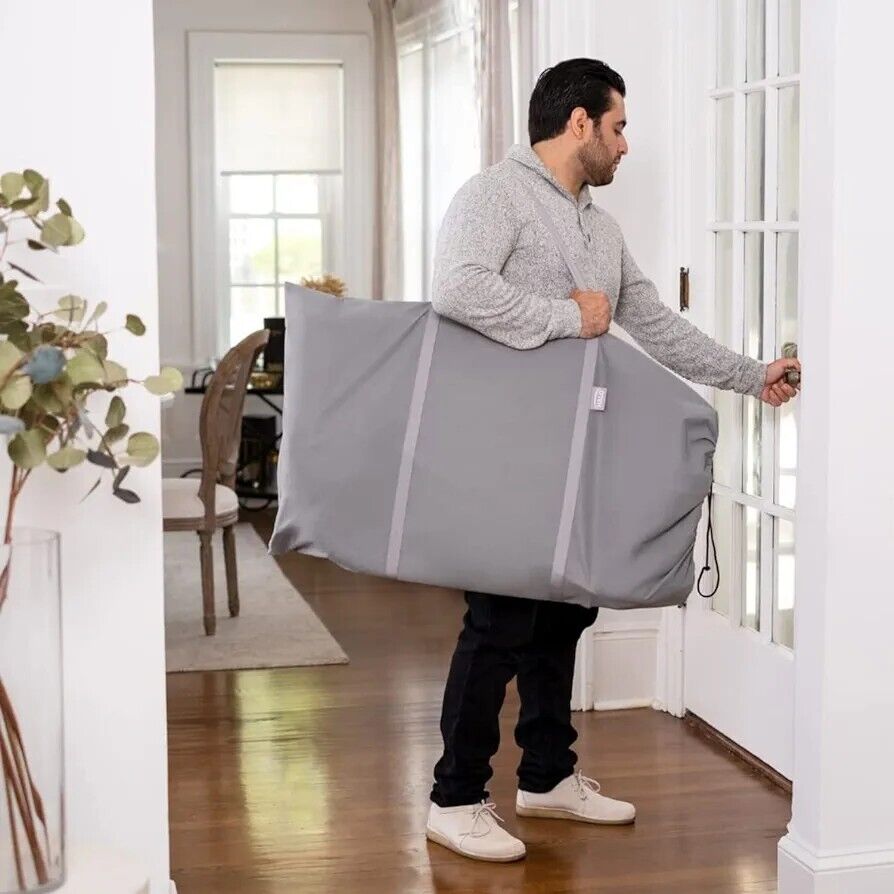 A man carrying a grey travel bag for the halo baby bassinet sleeper, designed for convenience and mobility