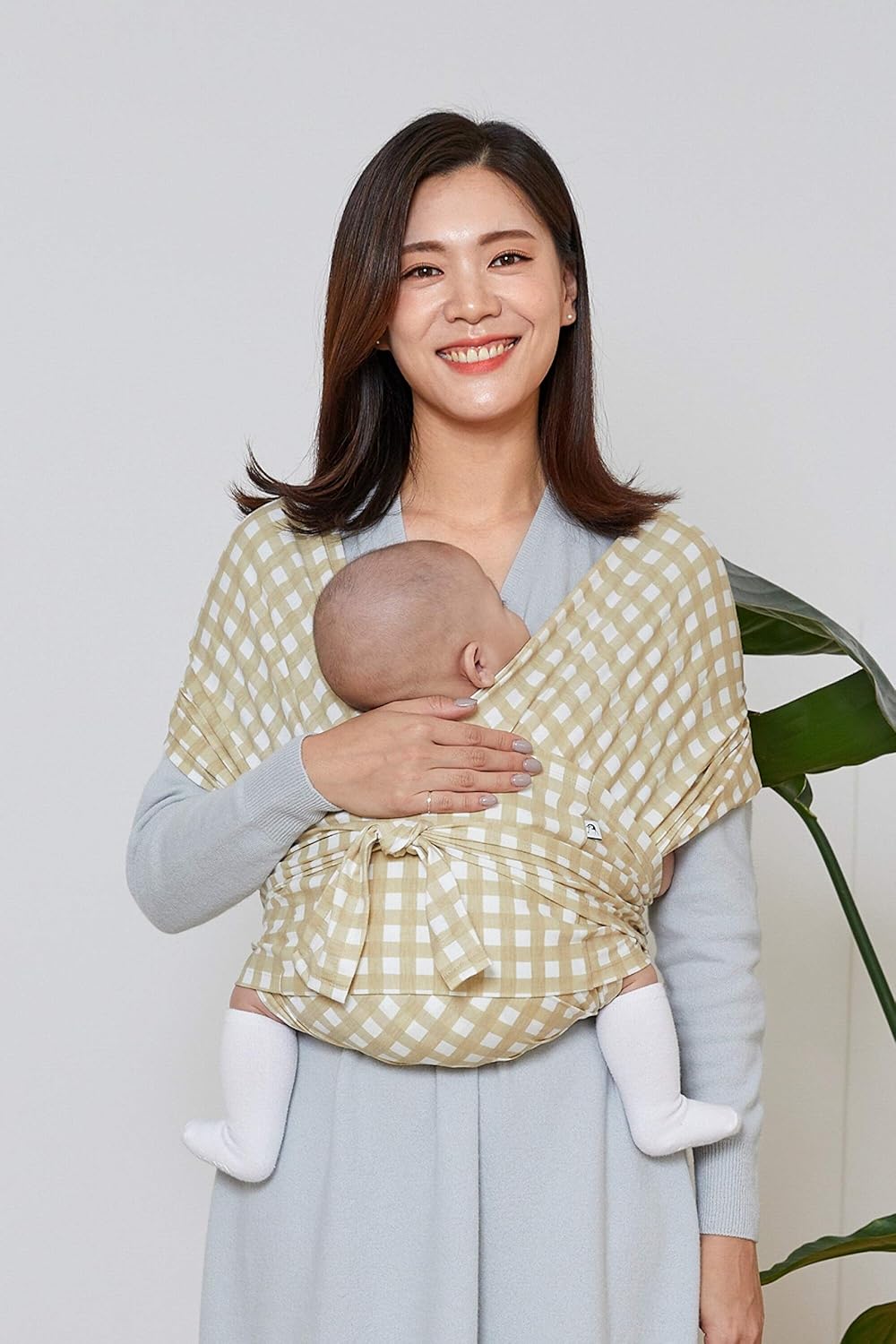 Konny lightweight infant carrier for mums in beige gingham, comfortably holding a baby close