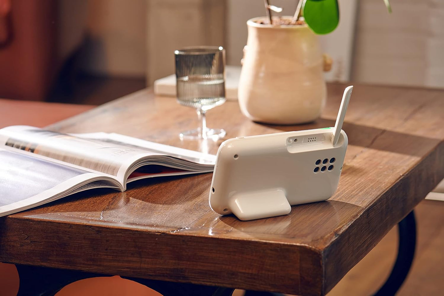 Motorola video baby monitor on a table next to a glass of water and an open magazine