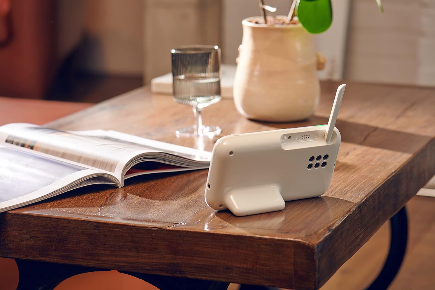 Motorola video baby monitor on a table next to a glass of water and an open magazine