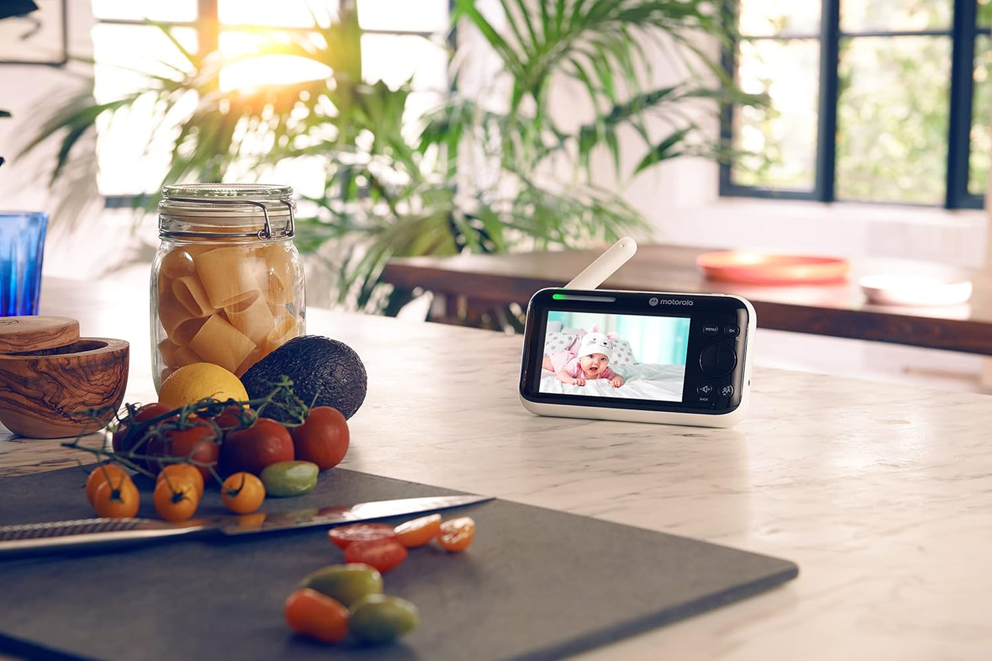 Motorola video baby monitor displaying a baby on its screen, set on a kitchen counter