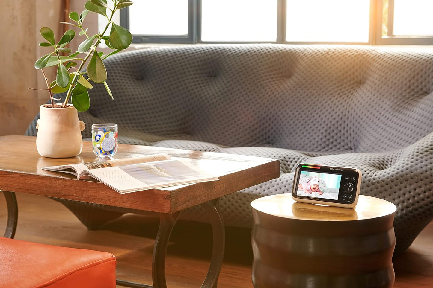 Motorola video baby monitor on a side table showing a clear image of a baby in a cosy living room setting