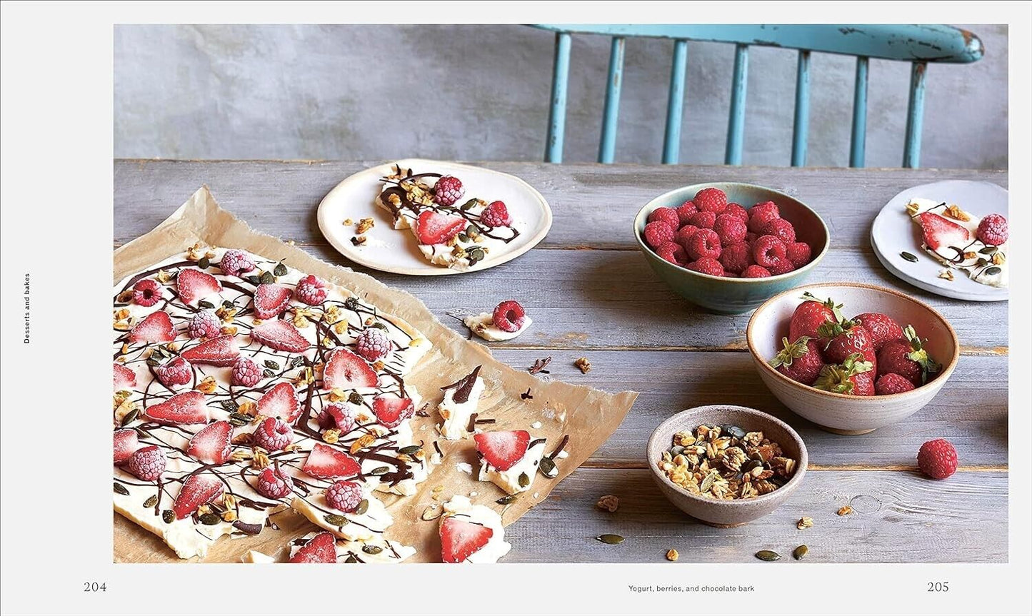 Pregnancy nutrition book featuring healthy dessert recipes with strawberries and raspberries on a kitchen table