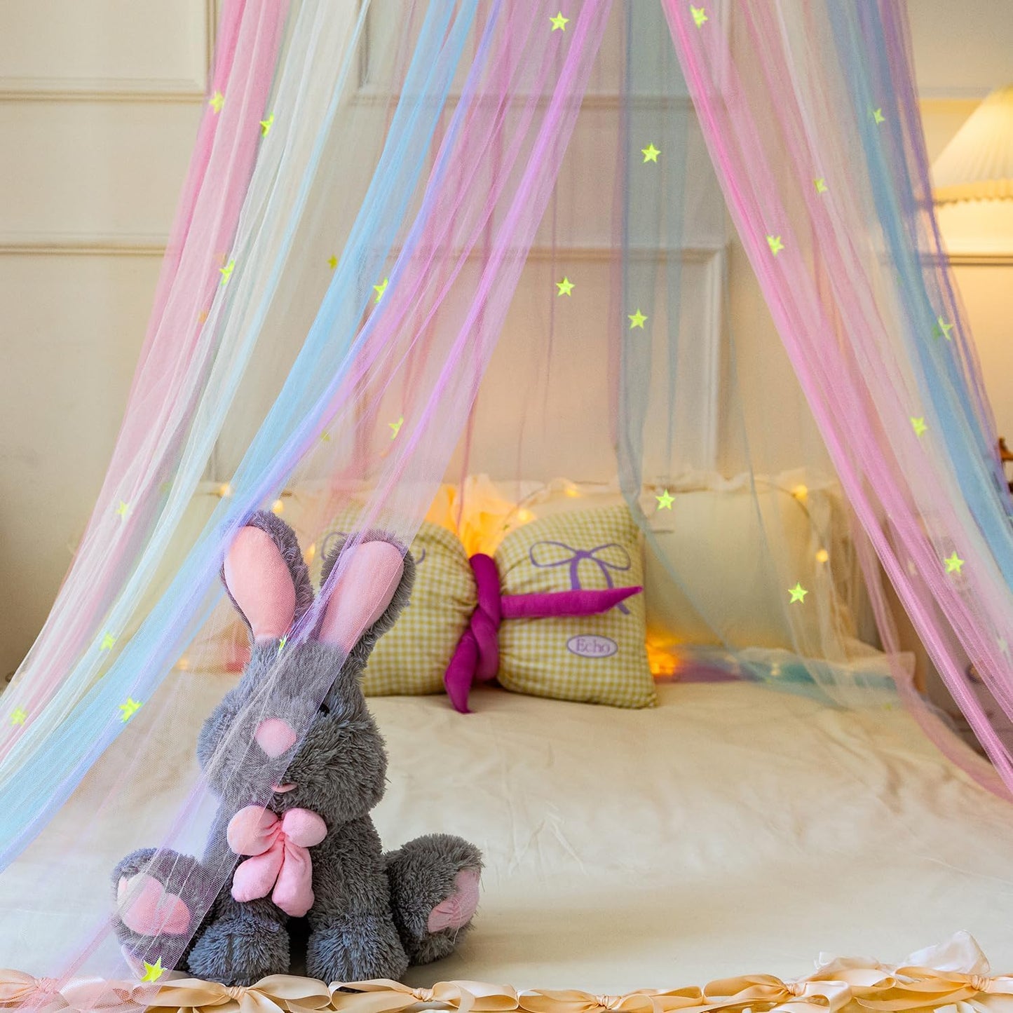 Princess rainbow bed canopy with pastel colours and star decorations over a child’s bed with plush toys