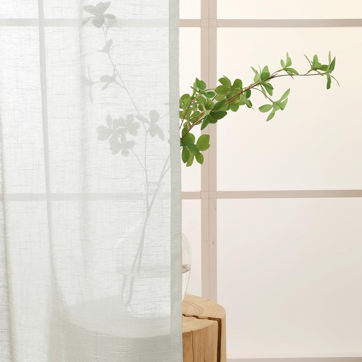 Silver grey semi sheer kitchen curtains letting in soft light with a green plant in the background