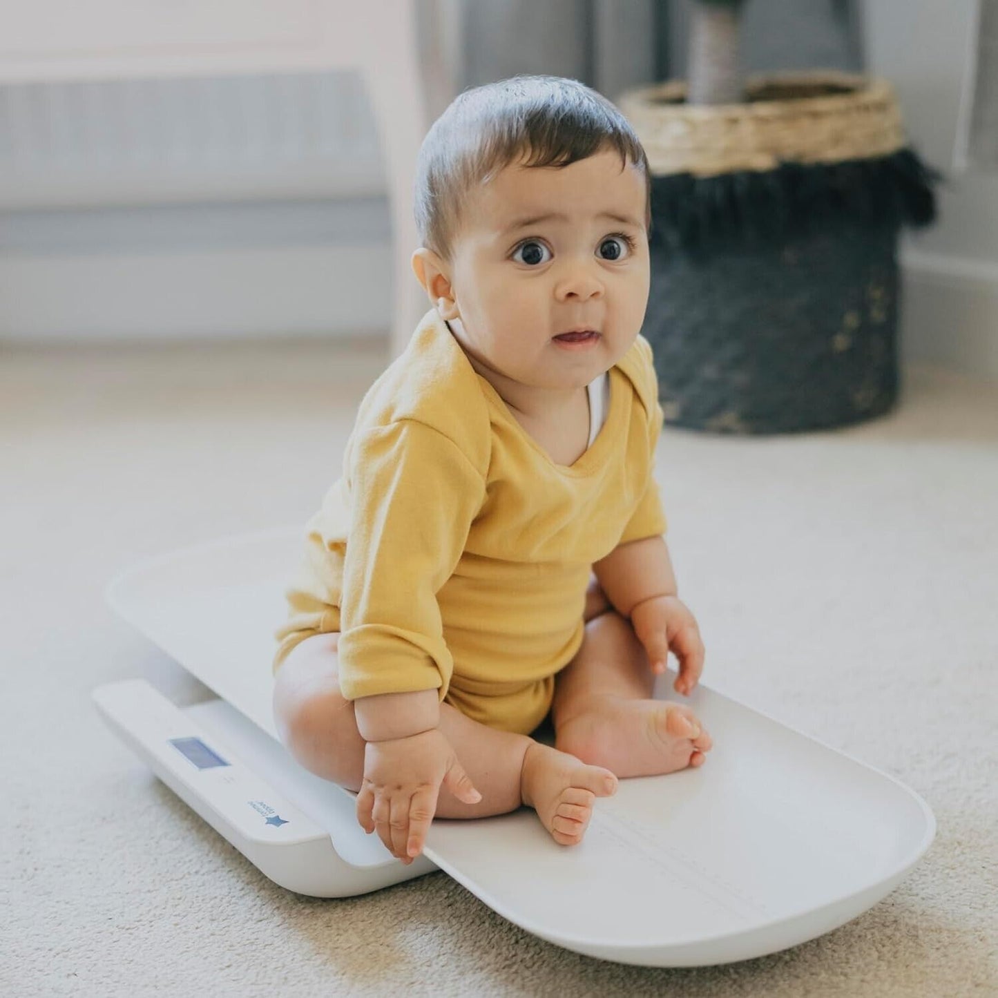 Tommee Tippee digital baby scales featuring a sleek design and a baby sitting on them for accurate weight measurement
