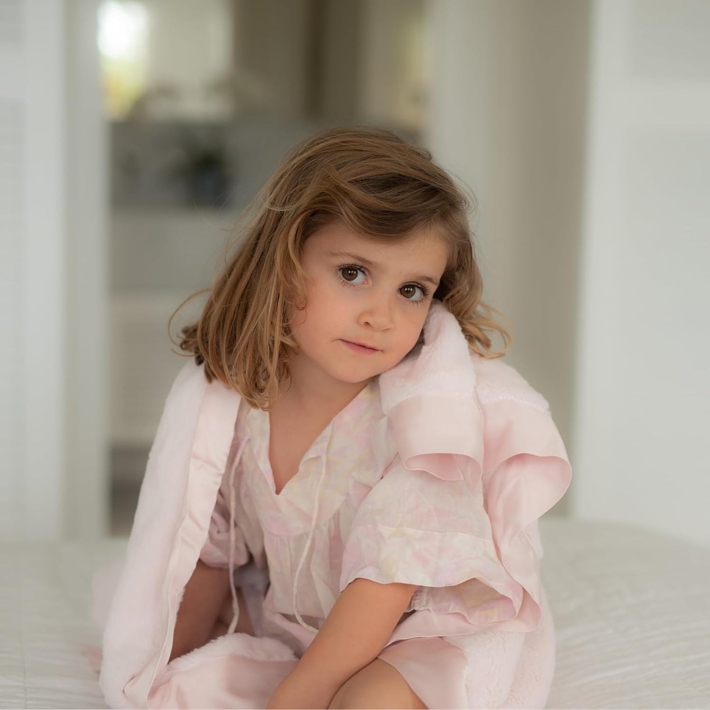 Adorable child wrapped in a pink baby chenille blanket, adding a touch of warmth and comfort