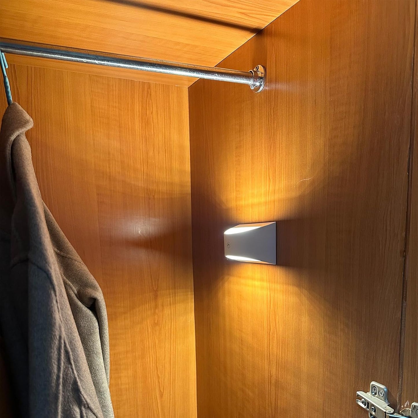 Joyes LED closet light mounted on wooden wardrobe wall illuminating hanging clothes