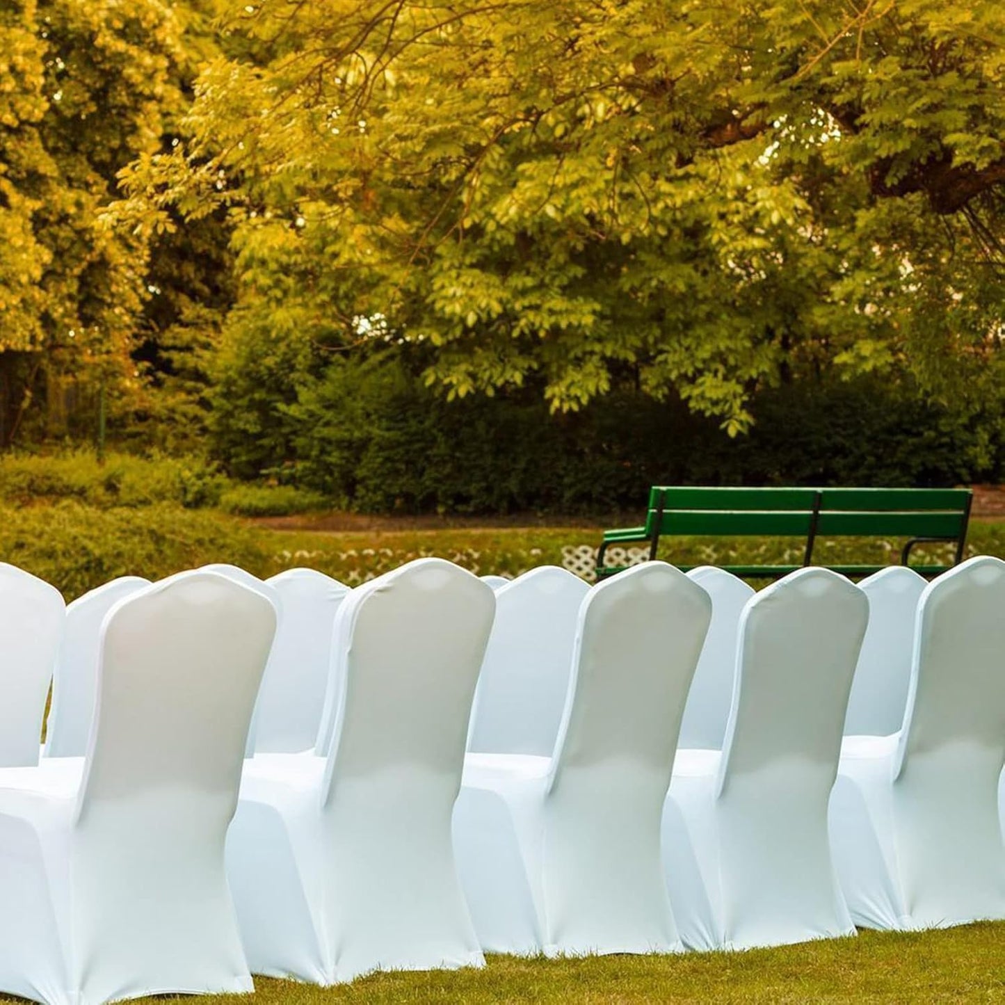 Elegant white polyester stretch chair covers arranged outdoors for event seating