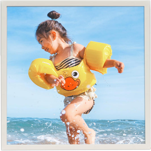 8x8 white photo frame showcasing a cheerful child playing at the beach with a yellow duck inflatable