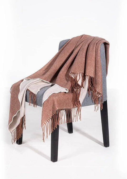 Cozy Australian wool throw blanket draped over a grey chair with elegant fringes
