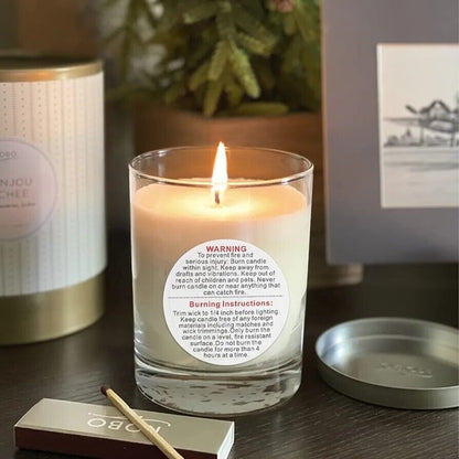Candle warning label stickers on a glass candle with lit wick and decorative background
