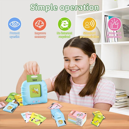 Child smiling while using an early educational voice card toy with flashcards on a table, promoting learning.