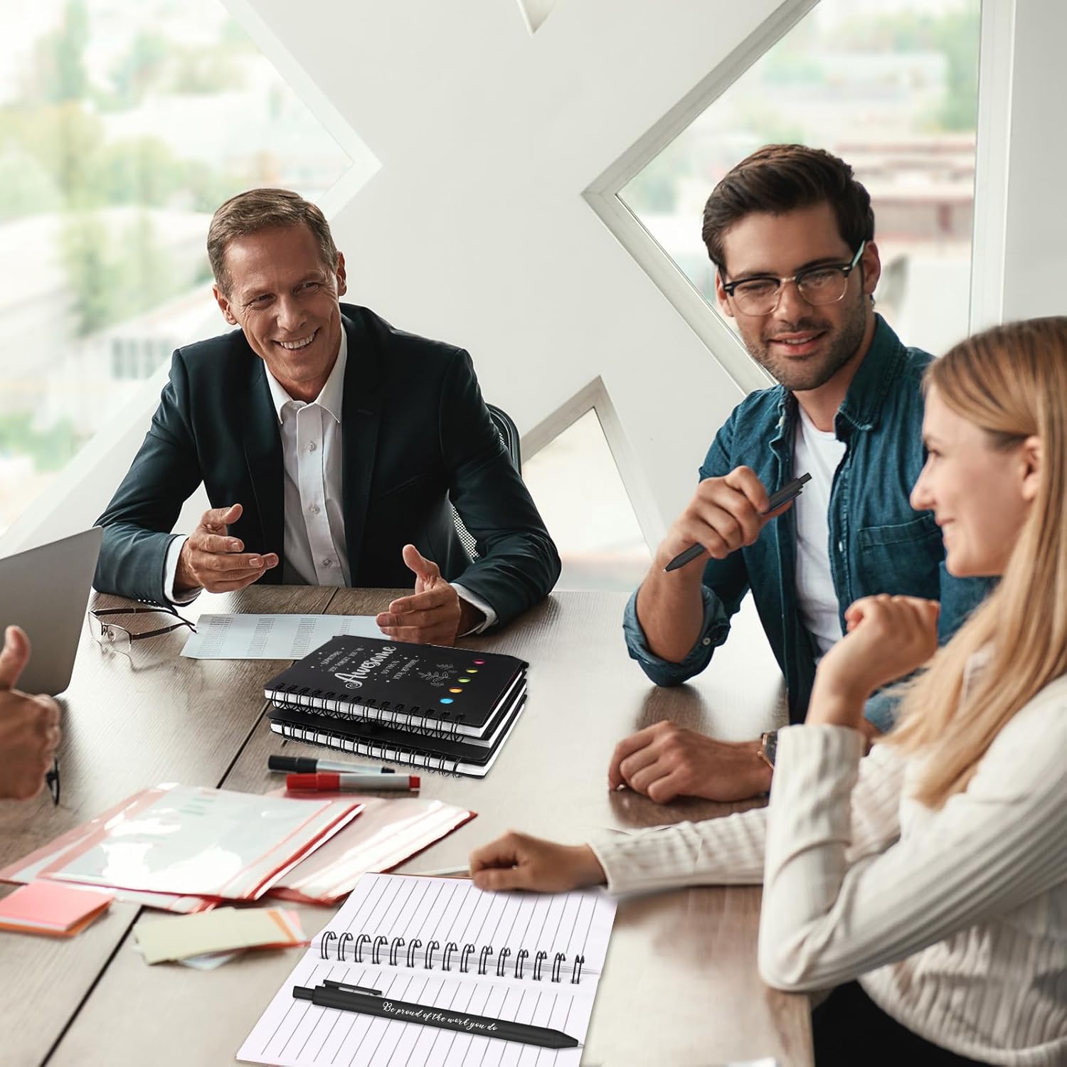 Group discussing employee appreciation gifts bulk in a modern office setting with books and notebooks