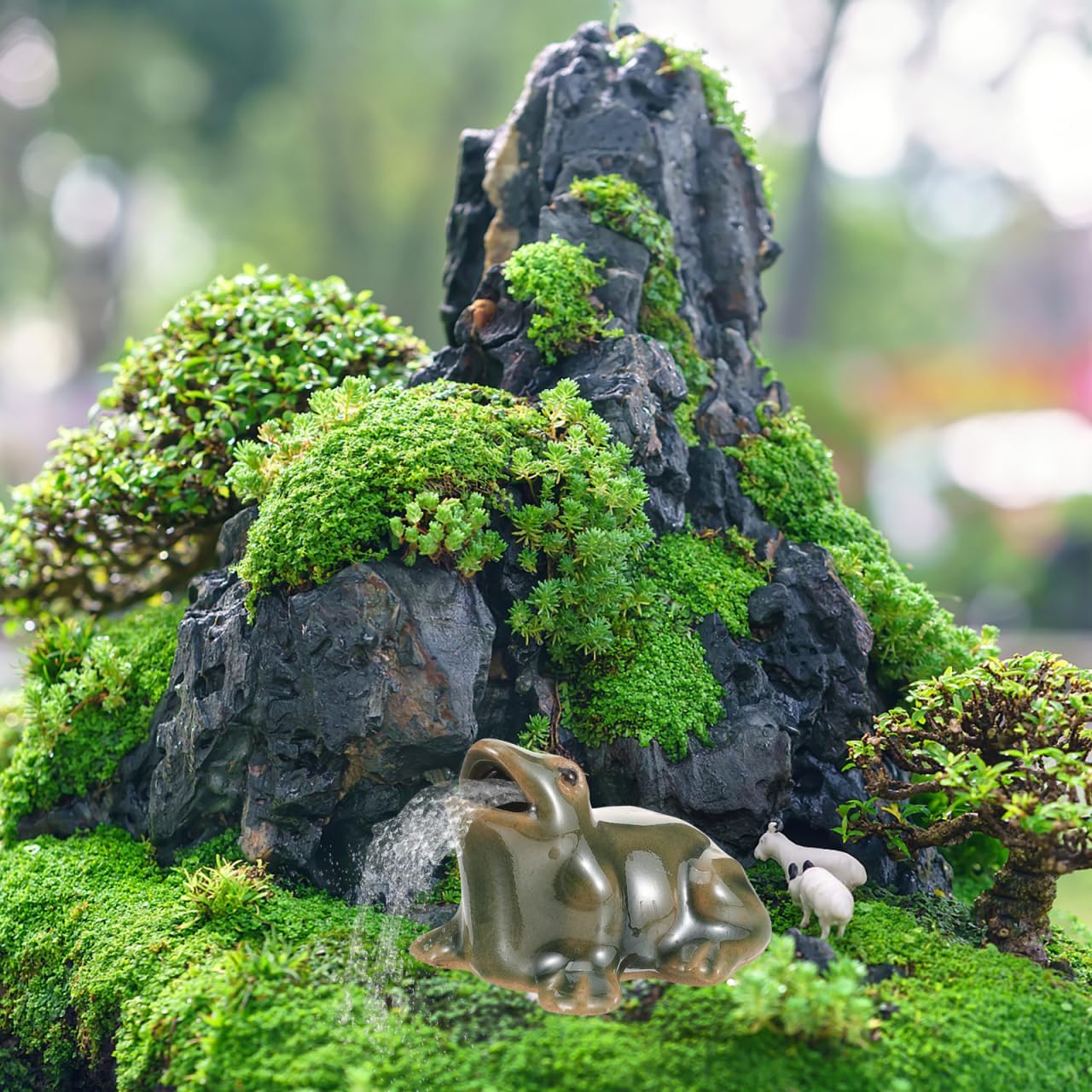 Yardwe frog water feature garden ornament atop a moss-covered rock with greenery.