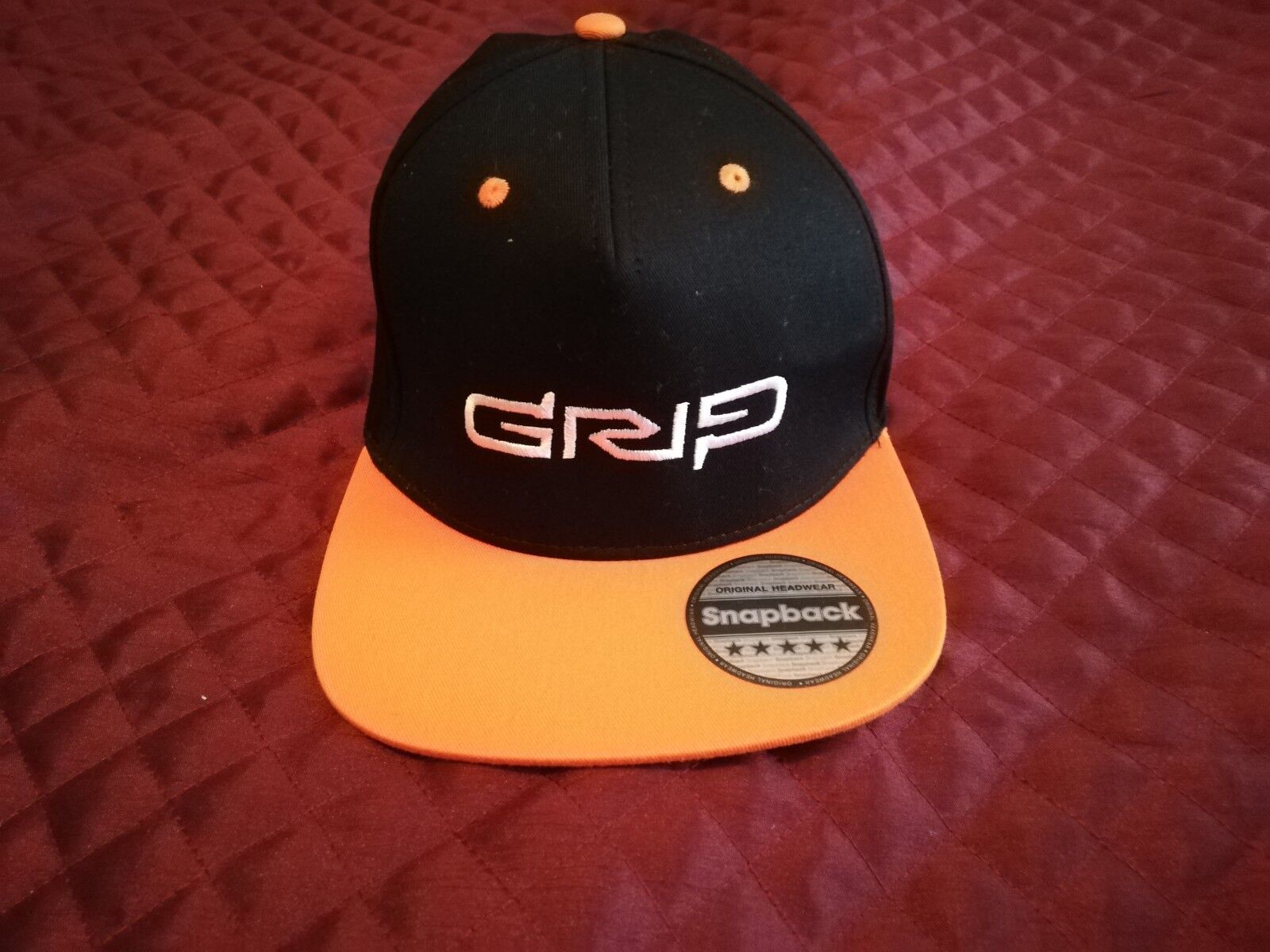 Grip video game snapback hat featuring a black and orange design for gamers