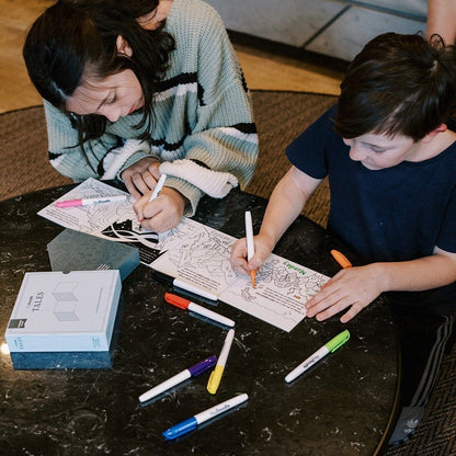 Children using markers in HeyDoodle Tales Natural Wonders activity book on a table