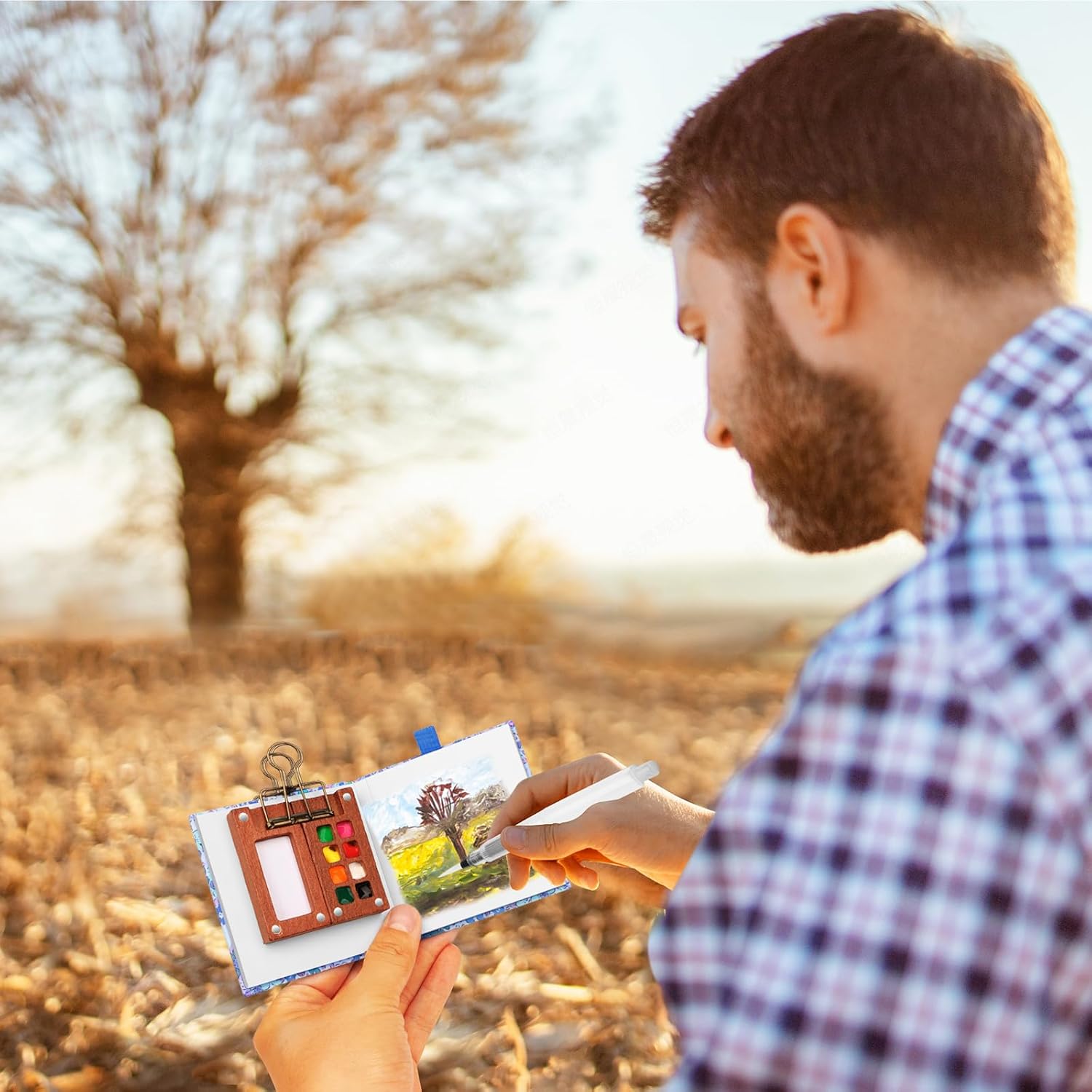 Artist using a mini watercolour paint set to create landscape art outdoors in natural surroundings