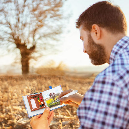 Artist using a mini watercolour paint set to create landscape art outdoors in natural surroundings