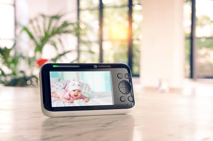 Motorola video baby monitor displaying a baby lying on a soft surface in a well-lit room