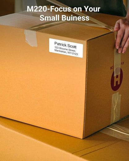 Phomemo M220 portable barcode printer with a label on a brown shipping box for efficient logistics