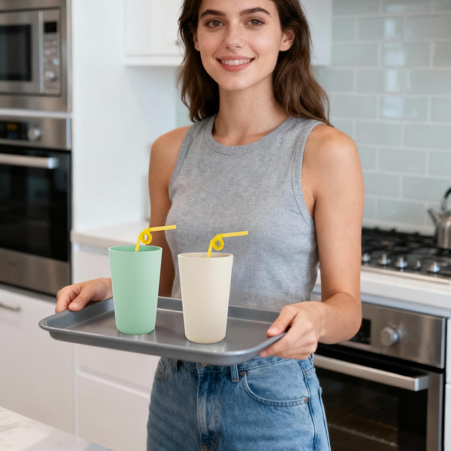 Young woman serving reusable plastic drinking cups on a tray in a modern kitchen