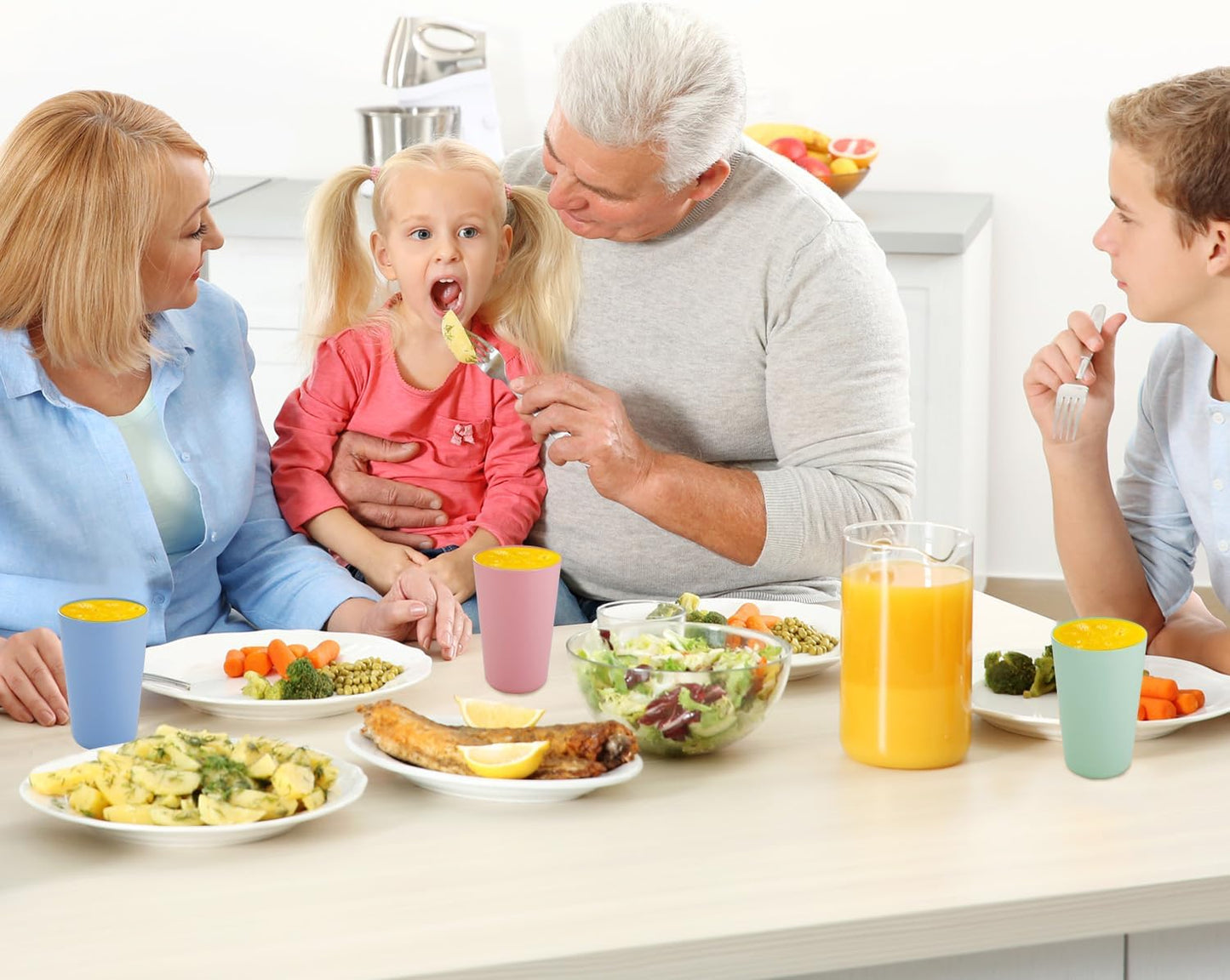 Family enjoying a meal with reusable plastic drinking cups in vibrant colours on the dining table