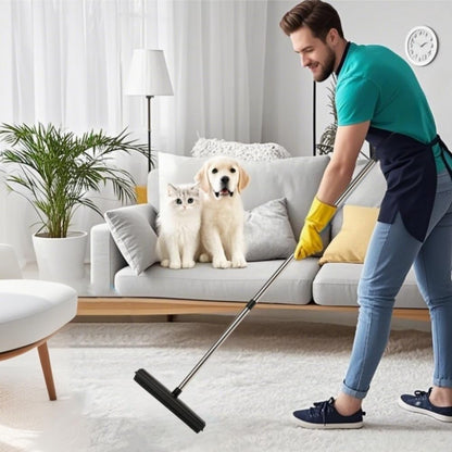 Man using a rubber broom for pet hair removal on carpet with dog and cat nearby