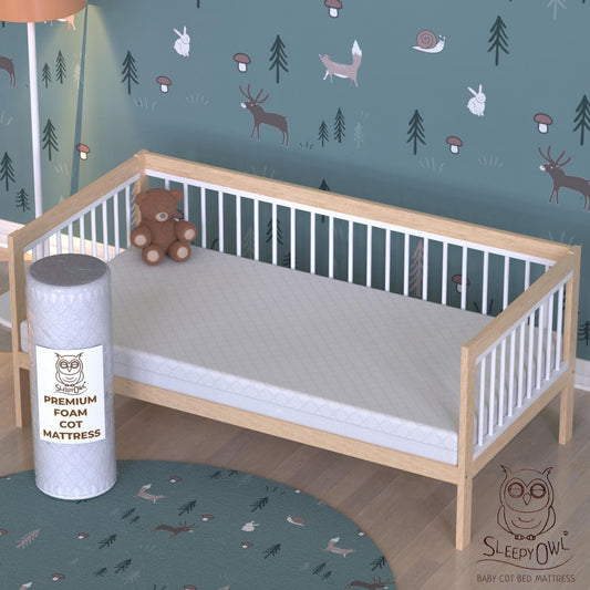 Sleepy Owl premium foam cot mattress displayed next to a wooden cot in a nursery setting