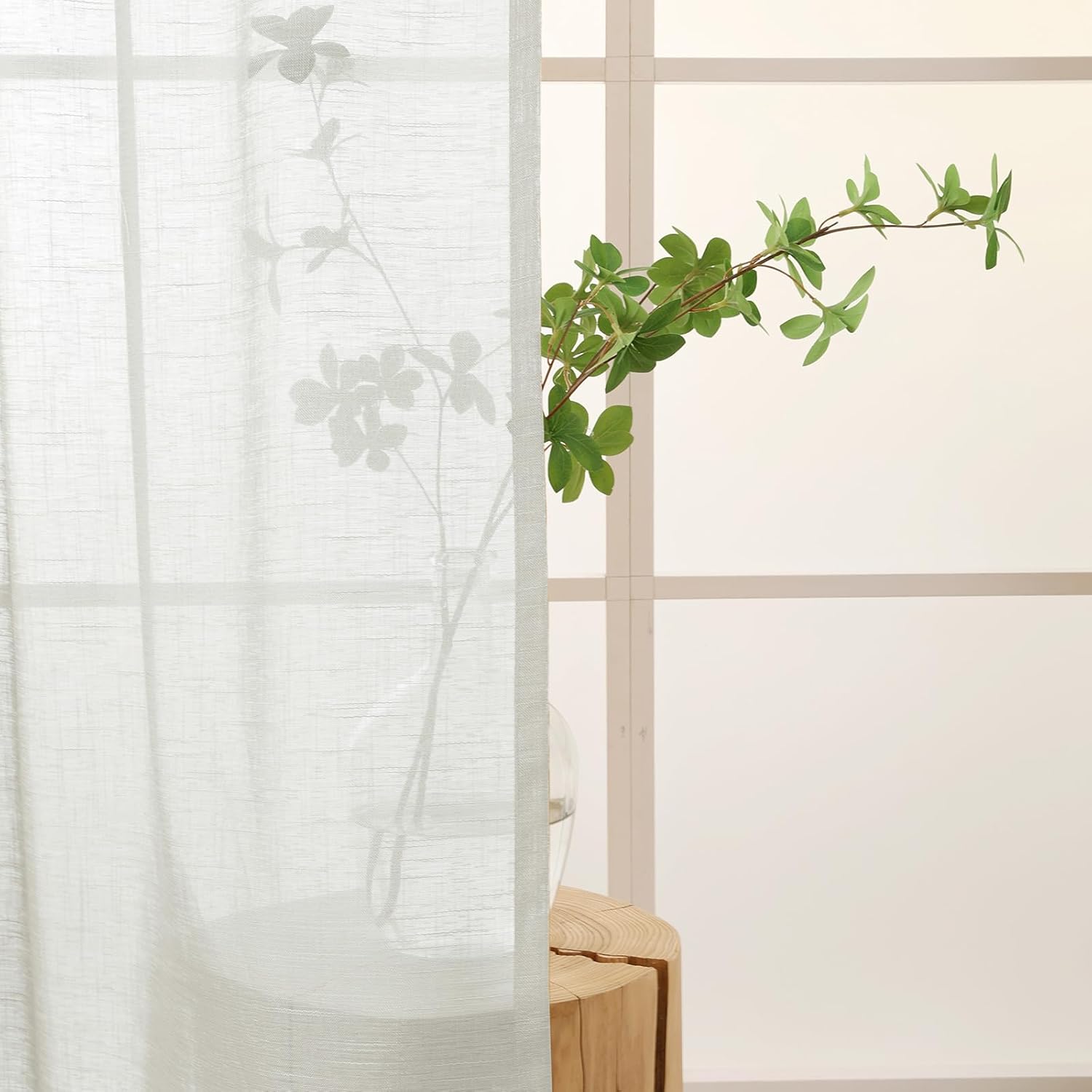 Silver grey semi sheer kitchen curtains letting in soft light with a green plant in the background