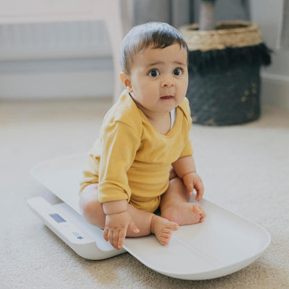 Tommee Tippee digital baby scales featuring a sleek design and a baby sitting on them for accurate weight measurement