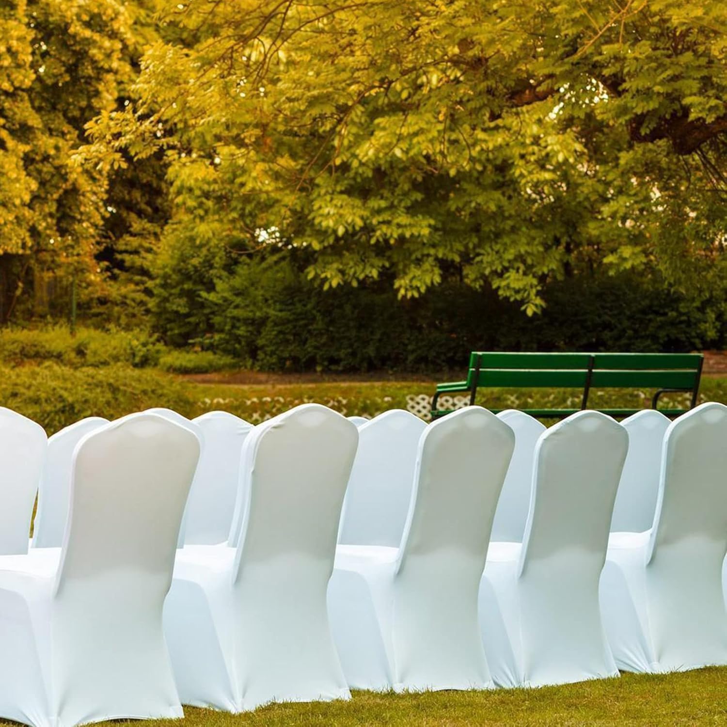 Elegant white polyester stretch chair covers arranged outdoors for event seating